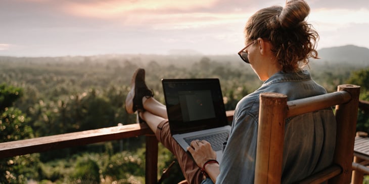 Eine Dame sitz im Urlaub am Laptop und  schließt eine Versicherungab