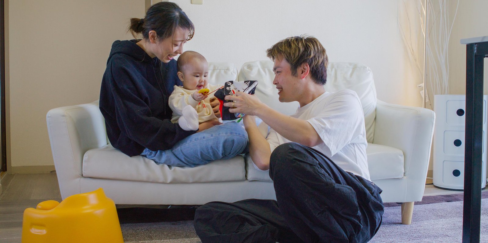 junge Eltern sitzen auf der Couch und spielen mit Baby