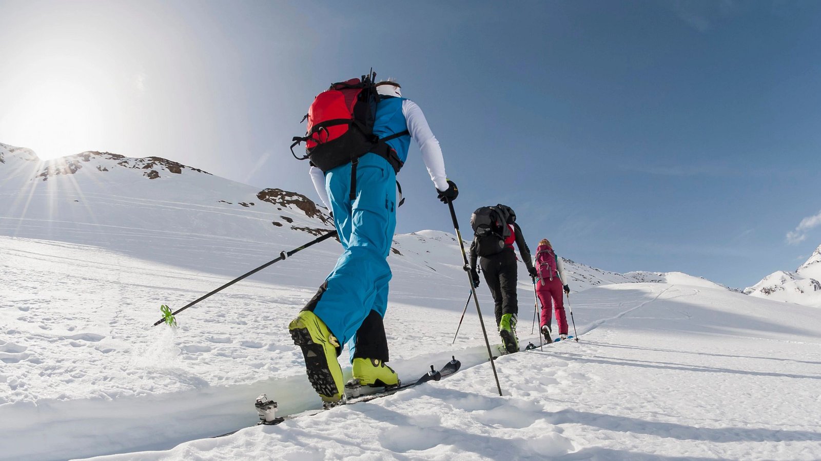 Tourengeher gehen auf eine verschneite Bergspitze.