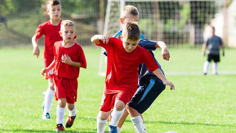 Kinder spielen in roten Dressen Fußball | Zurich Unfallversicherung