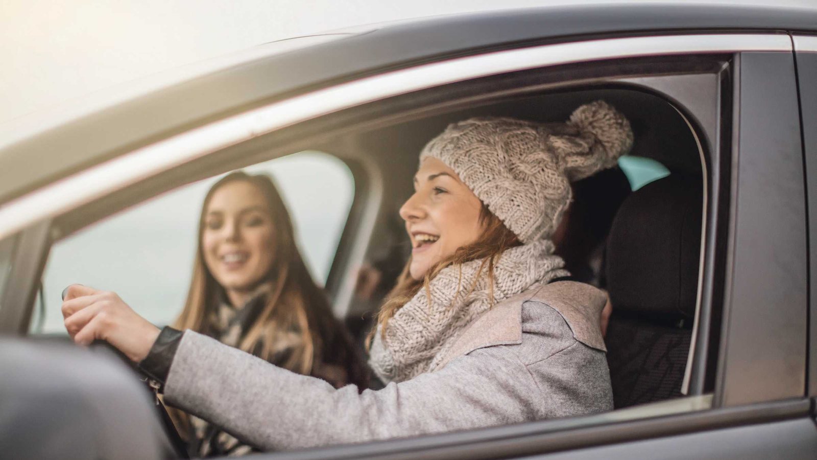 Zwei Damen fahren gut gelaunt im Auto.