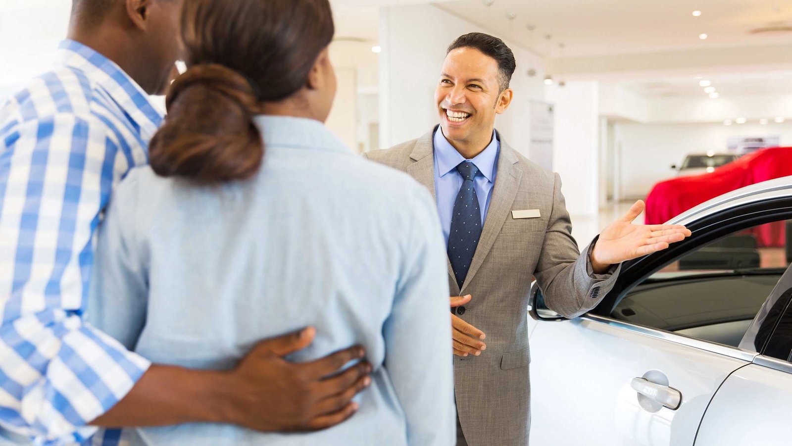 Ein Verkäufer zeigt einem interssiertem Pärchen einen Neuwagen.