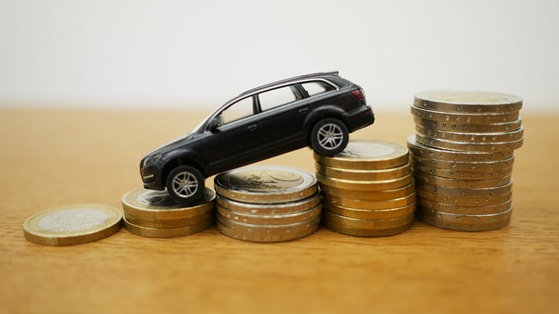 Ein Spielzeugauto fährt über einen Stapel Euromünzen