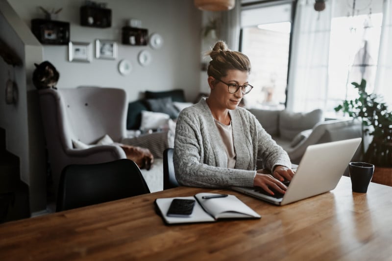 Eine Dame sitzt zuhause vor dem Laptop und überprüft ihre Kfz-Versicherung