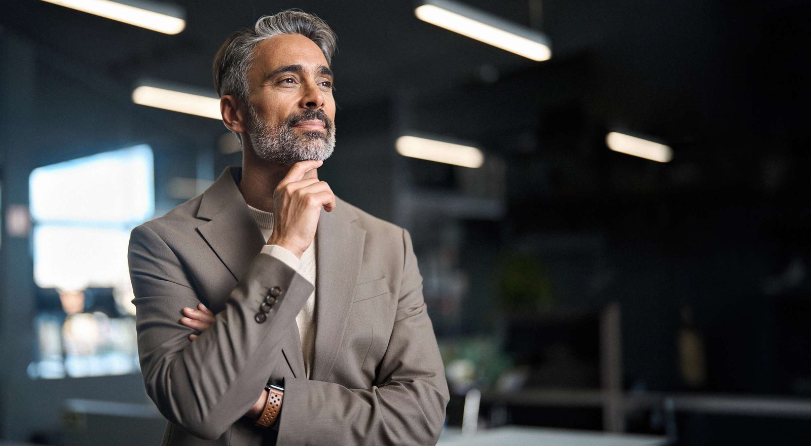 Ein Mann mit Bart hat die Hand am Kinn und blickt nachdenklich in die Ferne.