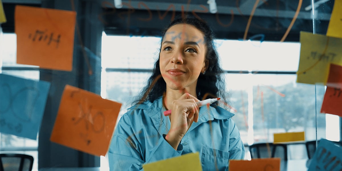 Dame steht vor einer Glaswand mit vielen Post its