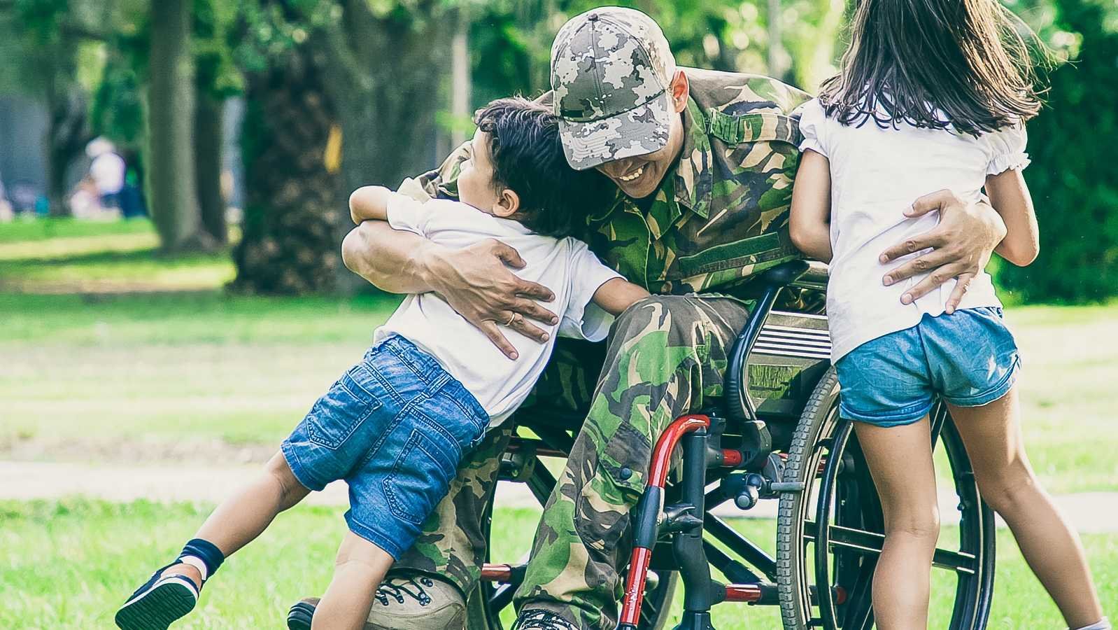 Ein Berufssoldat im Rollstuhl umarmt seine beiden Kinder.
