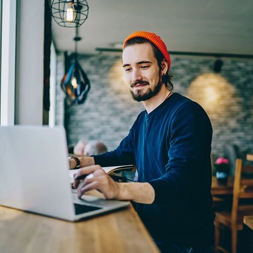 Junger Mann sucht auf dem Laptop nach Stellenanzeigen