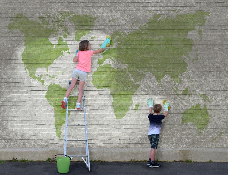 Kinder reinigen ein Graffiti das die Kontinente zeigt