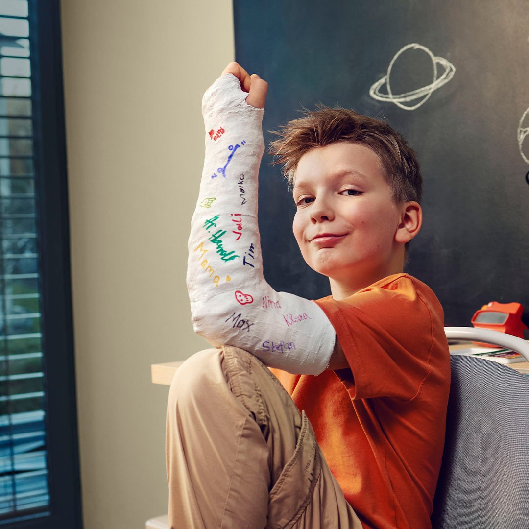 Bub ist trotz gebrochenem Arm im Gips fröhlich