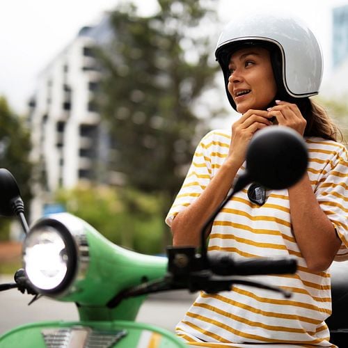 Frau macht sich auf ihrem Moped fahrbereit