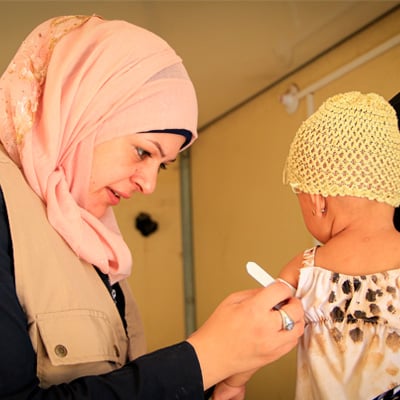 A health worker is checking the upper arm circumference of a young child 