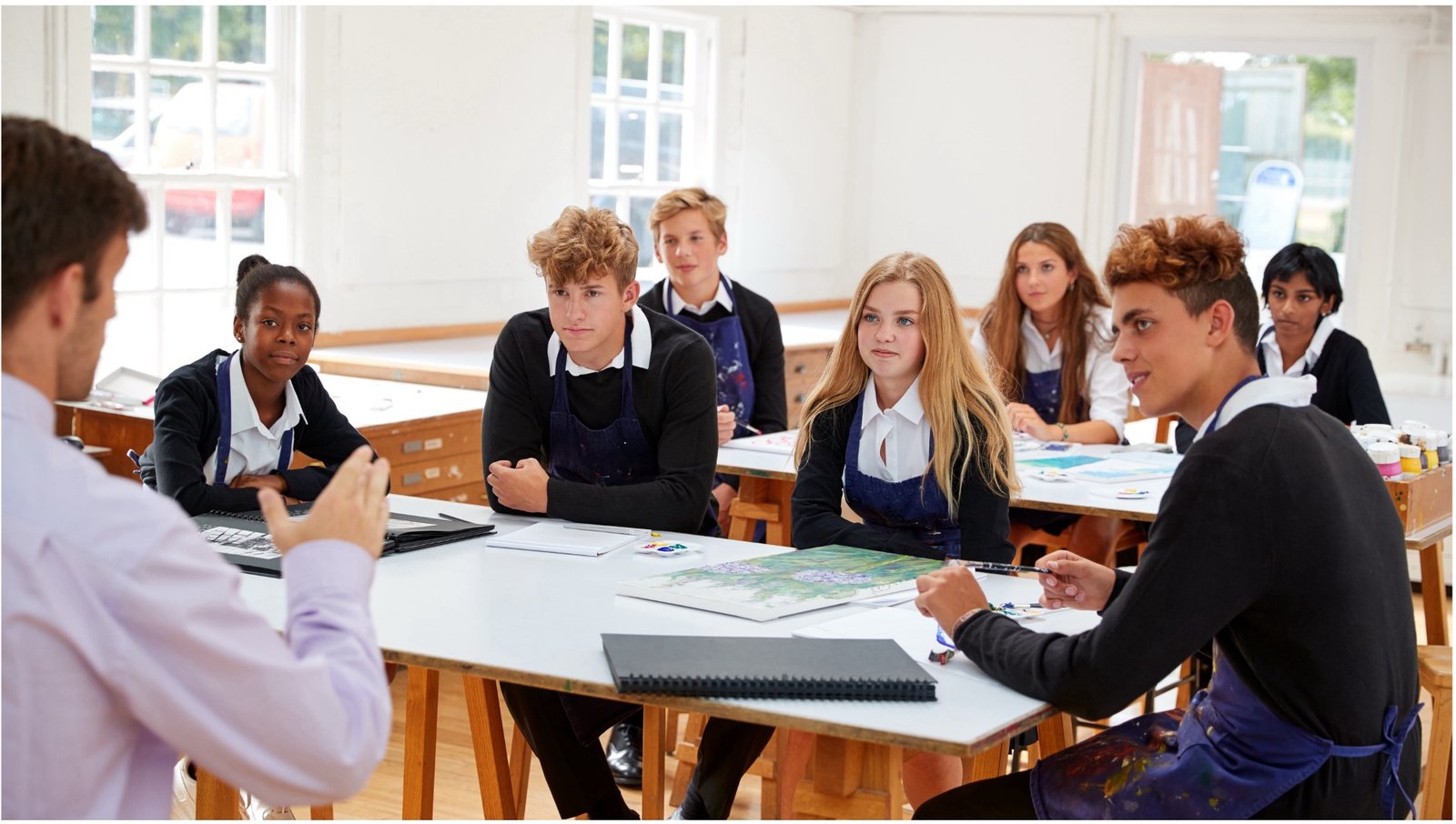 Teenage students in the classroom having a discussion with their teacher