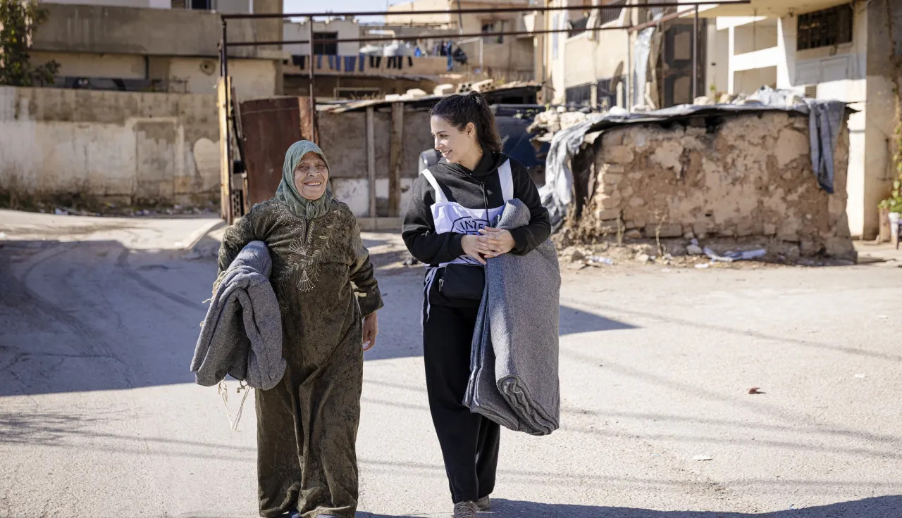 A staff member talks to a refugee during a distribution of hygiene articles, food and blankets in a refugee camp